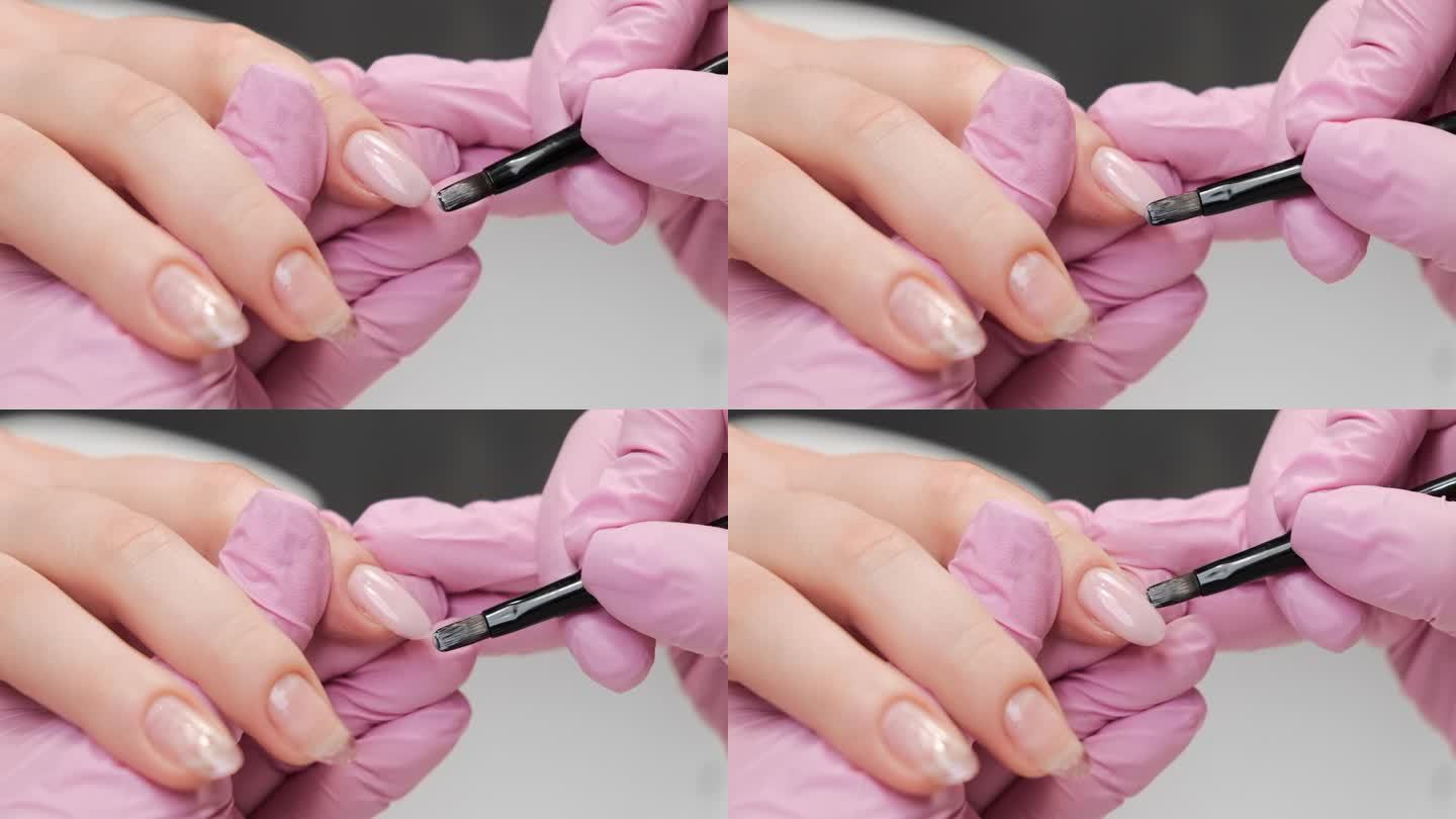 美甲师在美容院使用一种迷彩凝胶指甲油底。手持拍摄，特写。