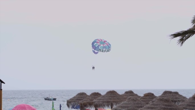 剪影人们在沙滩上对着晴朗的天空滑翔