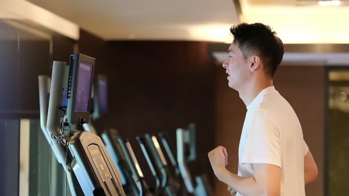 中国帅哥在健身房的跑步机上跑步的超慢镜头