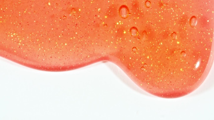 红色透明化妆品凝胶流体与分子气泡流动在白色的表面。微距镜头。液体乳霜凝胶透明化妆品样品纹理与泡沫。