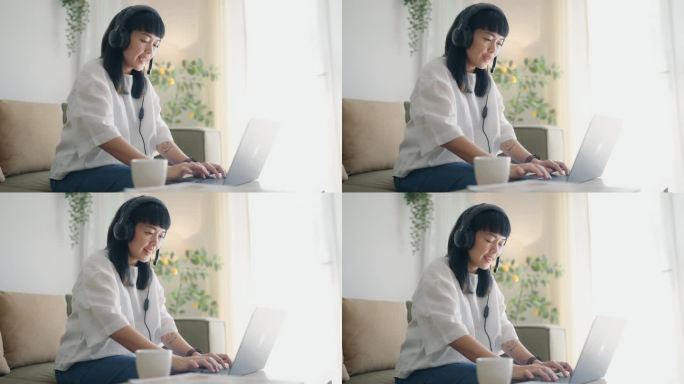 亚洲独立女商人使用耳机和笔记本电脑在家里的客厅工作。