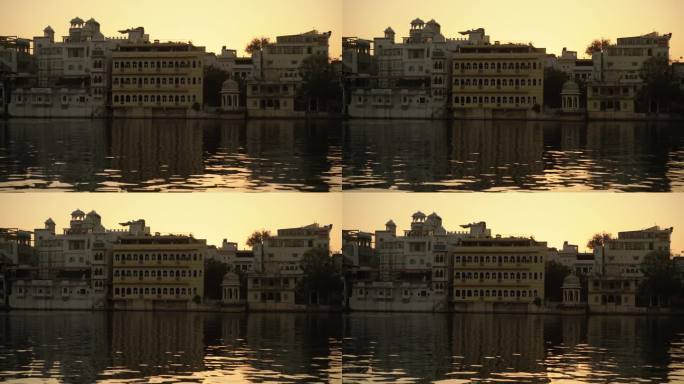 当太阳在印度乌代普尔的皮丘拉湖下下沉时，优雅的鸭子在水面上滑行，与令人惊叹的建筑的宁静背景相辅相成，