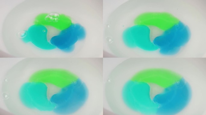 洗衣凝胶胶囊与洗衣粉在热水中溶解。蓝绿色洗衣液的全画幅镜头
