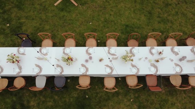 室外绿色草坪上的节日餐桌和木椅的鸟瞰图。从婚礼上的餐桌上看。婚礼. .