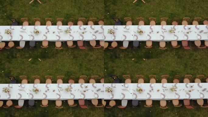 室外绿色草坪上的节日餐桌和木椅的鸟瞰图。从婚礼上的餐桌上看。婚礼. .