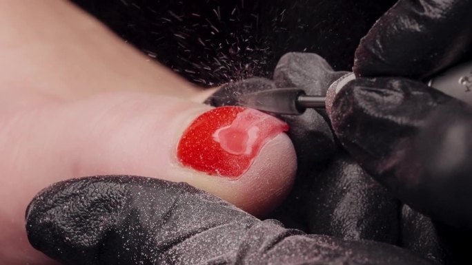 在足疗过程中，亮红色的指甲油被缓慢地从脚趾上移除，所有的凝胶都飞了出来