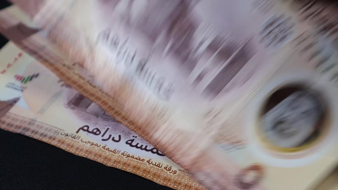 一名男子正在数阿拉伯联合酋长国迪拉姆钞票，这是新发行的具有增强安全功能的聚合物钞票。