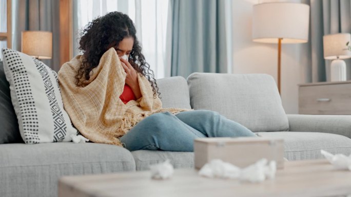 生病，过敏和女人打喷嚏在沙发上用纸巾擤鼻涕，清洁或病毒在家里。流感，压力和女性在客厅擤鼻涕感染病毒，