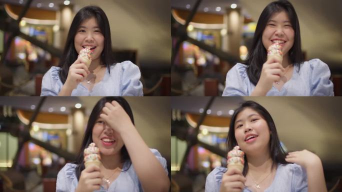 年轻的亚洲女子手持冰淇淋甜筒，微笑地看着镜头