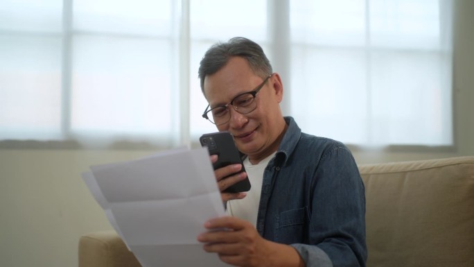 老年人阅读文件进行网上付款，退休人员付款
坐在家里沙发上用智能手机结账，为老客户提供银行服务。