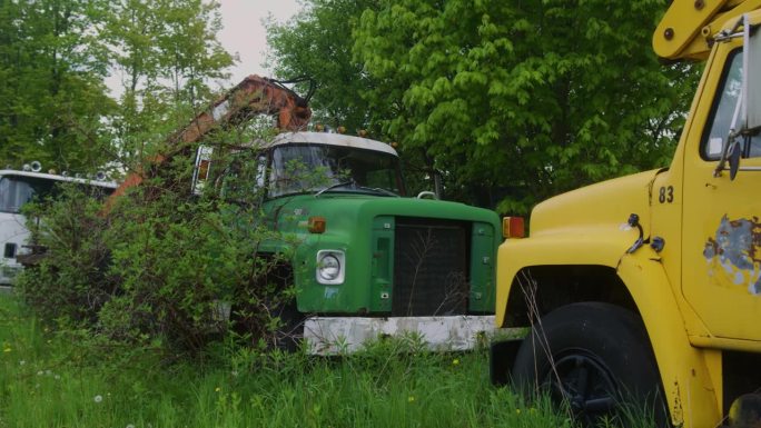 一辆老式校车和一辆大型老式卡车停在森林里腐烂的慢镜头。