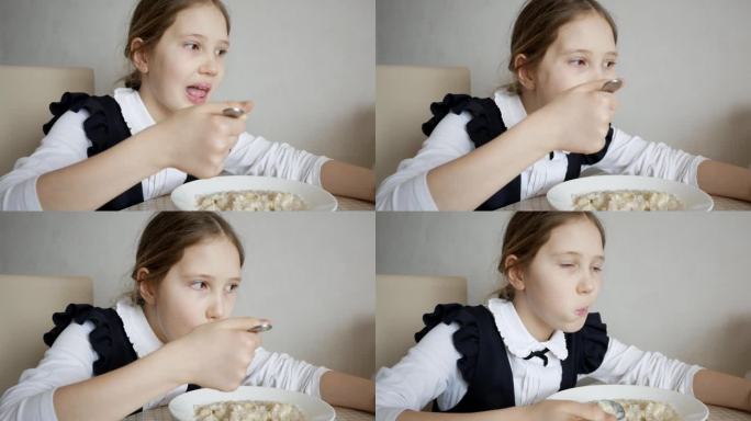 穿校服的女学生在学校食堂吃粥的特写。十几岁的女孩吃早餐或午餐。学校健康饮食的概念。