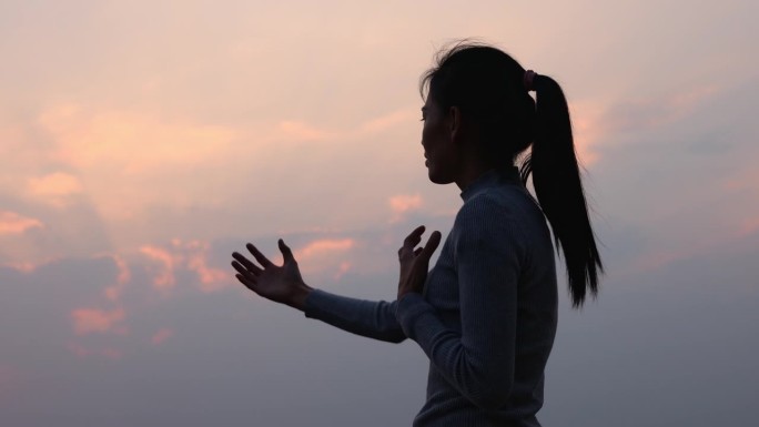 一个女人的剪影，她举起双臂敬拜上帝。天主教的复活节。为上帝而斗争和胜利。在精神上和宗教上赞美上帝。4