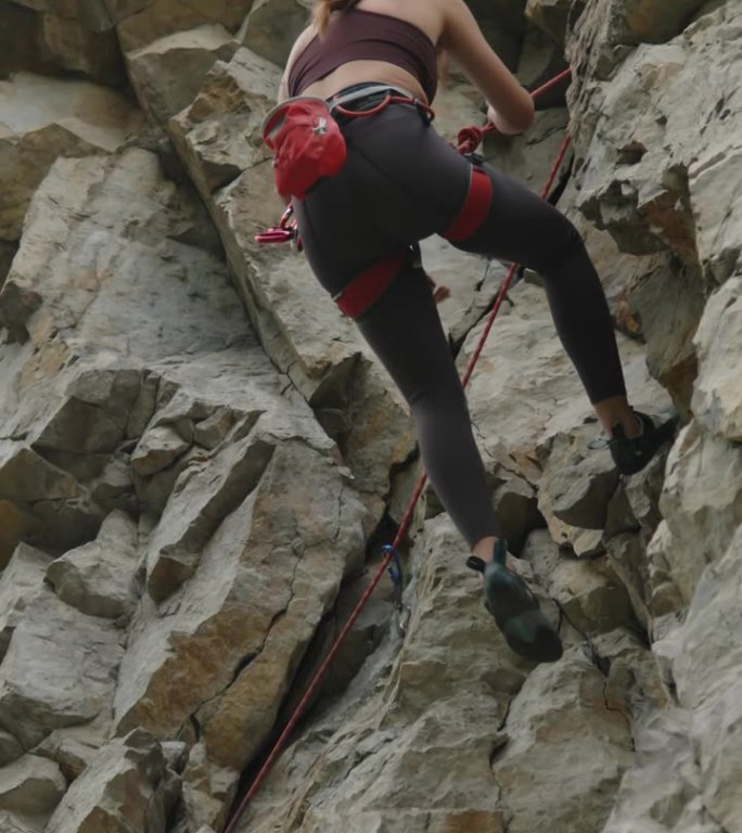 女孩攀爬后从岩面滑下