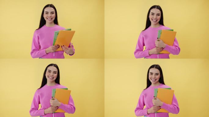 可爱的女人站在黄色背景上，手里拿着抄写本。穿着粉色衣服的有能力的大学生，对新学年感到兴奋，准备学习有
