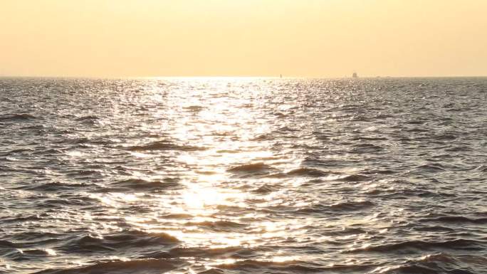 黄昏海边夕阳西下水面波光粼粼远处船舶烟囱