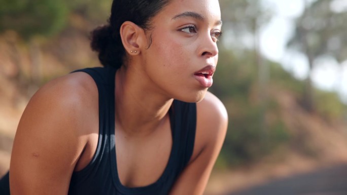 女性跑步者戴着耳机在街头跑步时停下来深呼吸并使用智能手表。运动与健康生活理念。