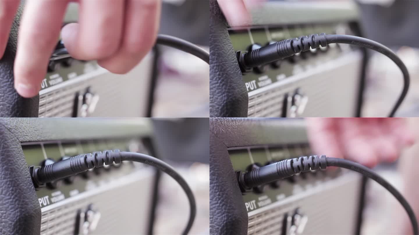 一名男子将吉他连接到放大器，并用手将电吉他插孔插入放大器。近距离，4K分辨率。