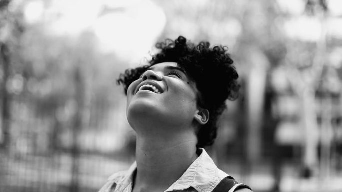 一位快乐沉思的巴西女性，20多岁，非洲裔，凝视着天空，黑白分明。单色肖像跟踪拍摄