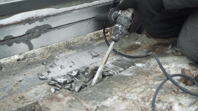 建筑工用锤子在墙上钻一个洞。冲击钻射孔器打孔特写