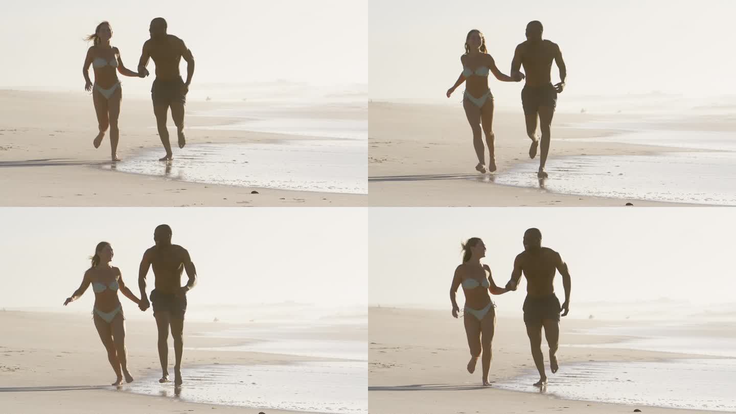 一对穿着泳装度假的情侣手牵着手沿着海滩岸线奔跑