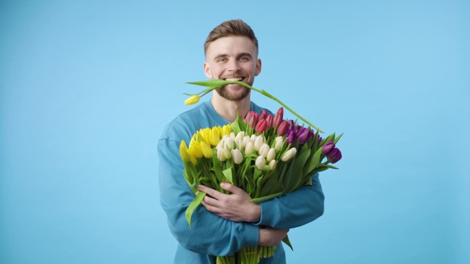 留着胡子的男人拿着一束蓝色背景的花