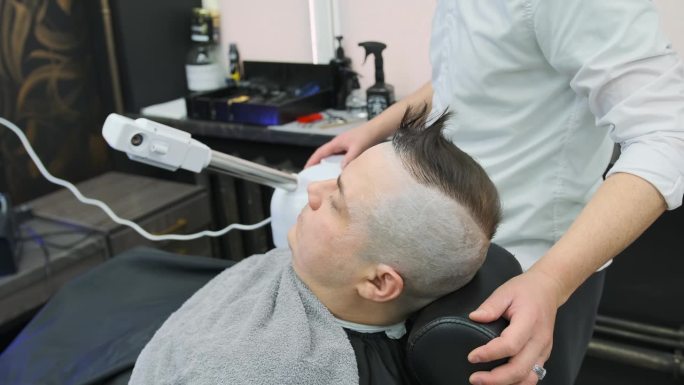理发师让顾客靠近蒸汽加湿器，让他在剃须前做好准备