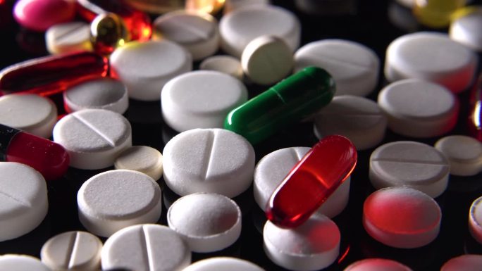 许多不同的药丸在黑色的桌子上旋转，维生素和膳食补充剂，每天服用的药物，预防性治疗，特写