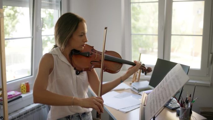 年轻的女小提琴家在家里练习小提琴