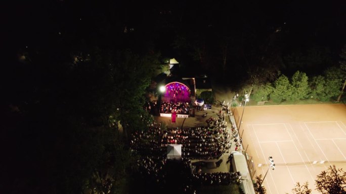 4k鸟瞰图:夜间公园灯光舞台上的现场音乐会