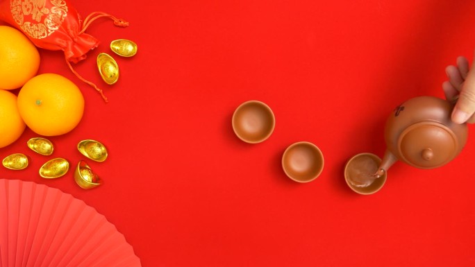 手持式茶壶，将茶倒入茶杯中，有中国农历新年的装饰