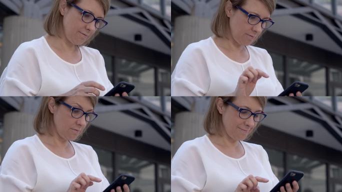 在户外，一位身穿白色衣服的黑发女子正全神贯注地发信息，用她的智能手机拉近距离。