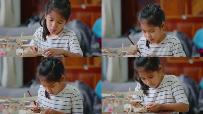 亚洲女孩正在用铅笔色给组装的木制玩具上色