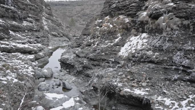 冬天的小溪流过布满雪块的岩石地形，阴天，自然光
