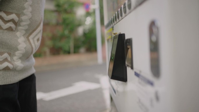 亚洲女性在自动售货机上用信用卡付款。