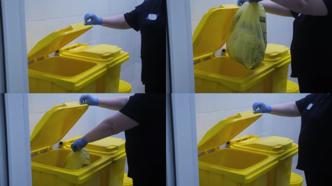 4 k的视频。医疗废物的概念，一个戴着蓝色手套的女性手打开一个黄色的水箱，放下一个垃圾袋。处置和贮存