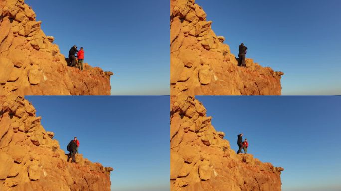 爸爸和儿子爬到山顶，顶着蓝天，站在山顶上看日落，举起双手