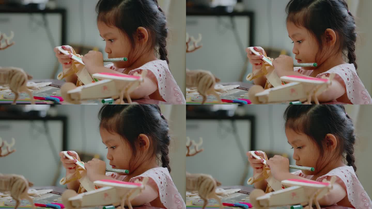 亚洲女孩正在用神奇的颜色给组装的木制玩具上色