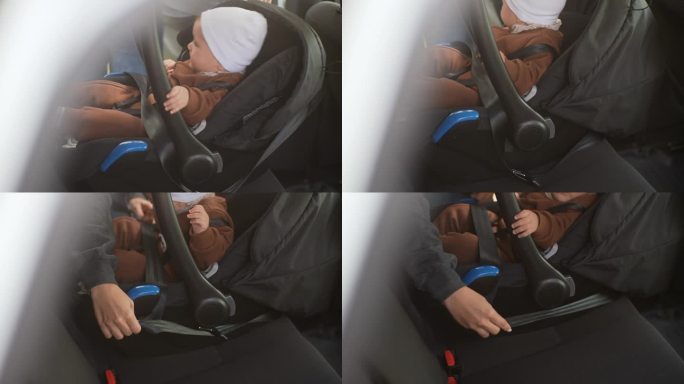 特写:无法辨认的父母正为坐在汽车后座上哭闹的男婴系安全带。乘车时系上安全带的伤心孩子。