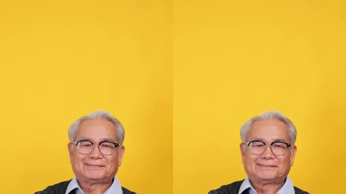 垂直夹。特写，老人微笑着看着镜头的肖像。孤立在工作室的黄色背景上。