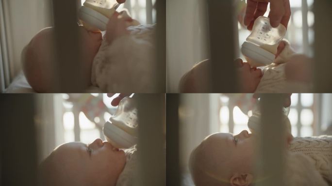 SLO MO滋养的爱:婴儿在阳光的怀抱中从奶瓶里喂奶时母亲的温柔关怀