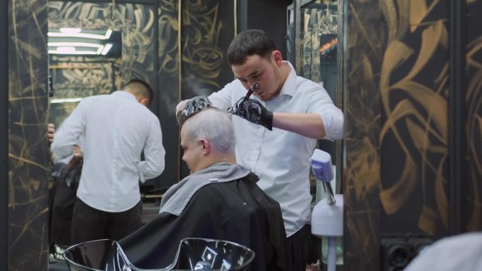 理发店里的理发师用直剃刀用肥皂泡沫给一个男人剃头。