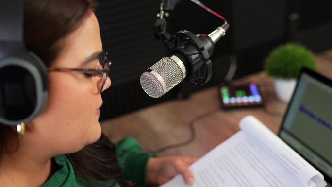 一个女人在广播电台对着麦克风说话，录制新一集的特写