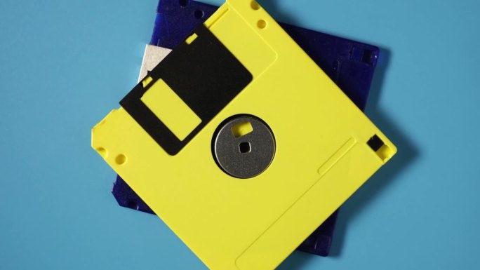 黄色复古3.5“软盘在蓝色背景，俯视图。计算的概念，计算机，存储，复古，磁盘和数据存储。软盘，4K视