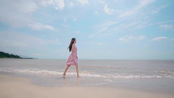 美女在海边漫步游玩遥望远方海水冲刷白沙滩