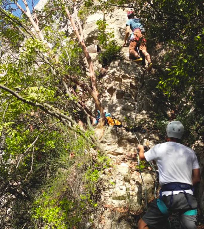 男性攀登者在密林中的攀岩岩上攀爬领袖技术。登山者戴上头盔和登山吊带。