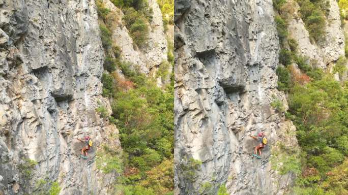 无人机视图创建一个新的攀登路线，使用凿岩机和旋转锤在攀登绳。登山者戴着红色的头盔。