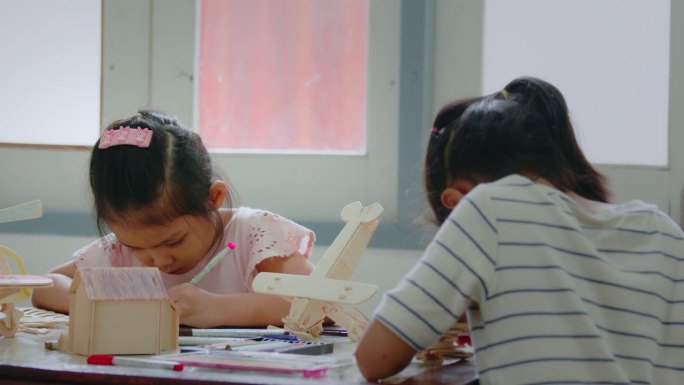 亚洲女孩和她的姐姐正在组装木制玩具上色