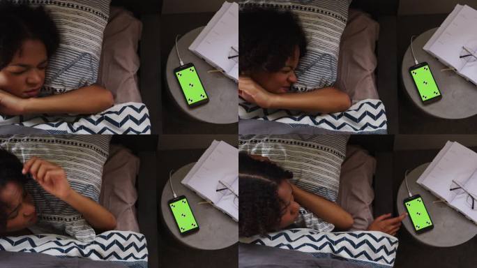 在一个睡觉的女人旁边的桌子上放着一个绿色屏幕的手机