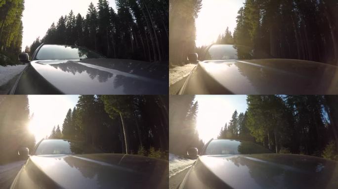 POV车顶摄像头，当汽车行驶在美丽的乡村道路，周围的云杉森林和日落的背景